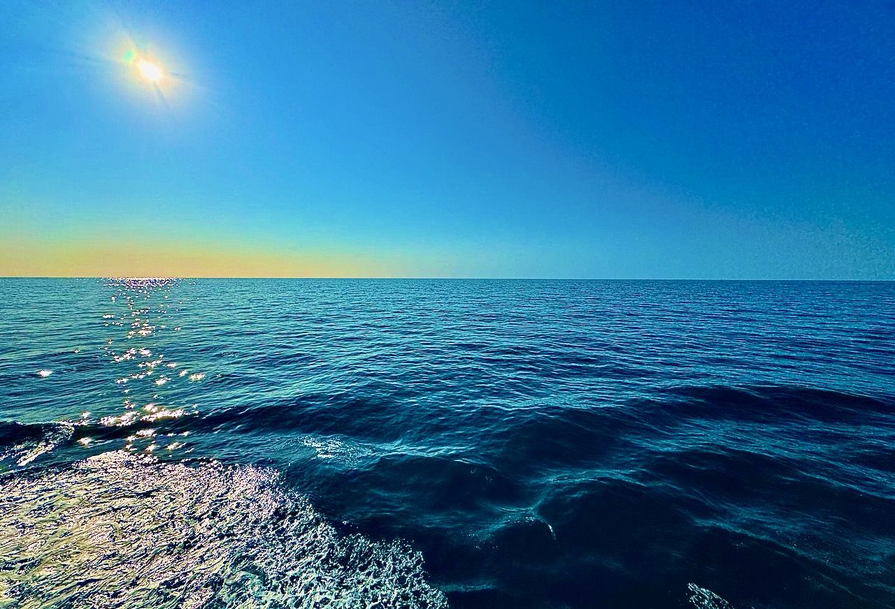 I image from our balcony of a book in the ocean the sun is high in the sky and the ocean is calm