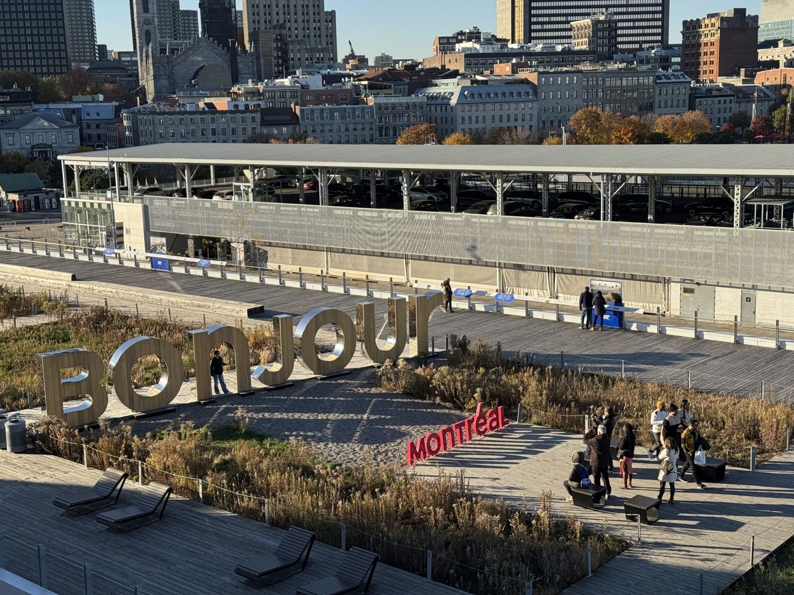 A sign that’s says bonjour Montreal. The letters are large three d shapes set on the crowd. People mill around taking photos among the letters. 