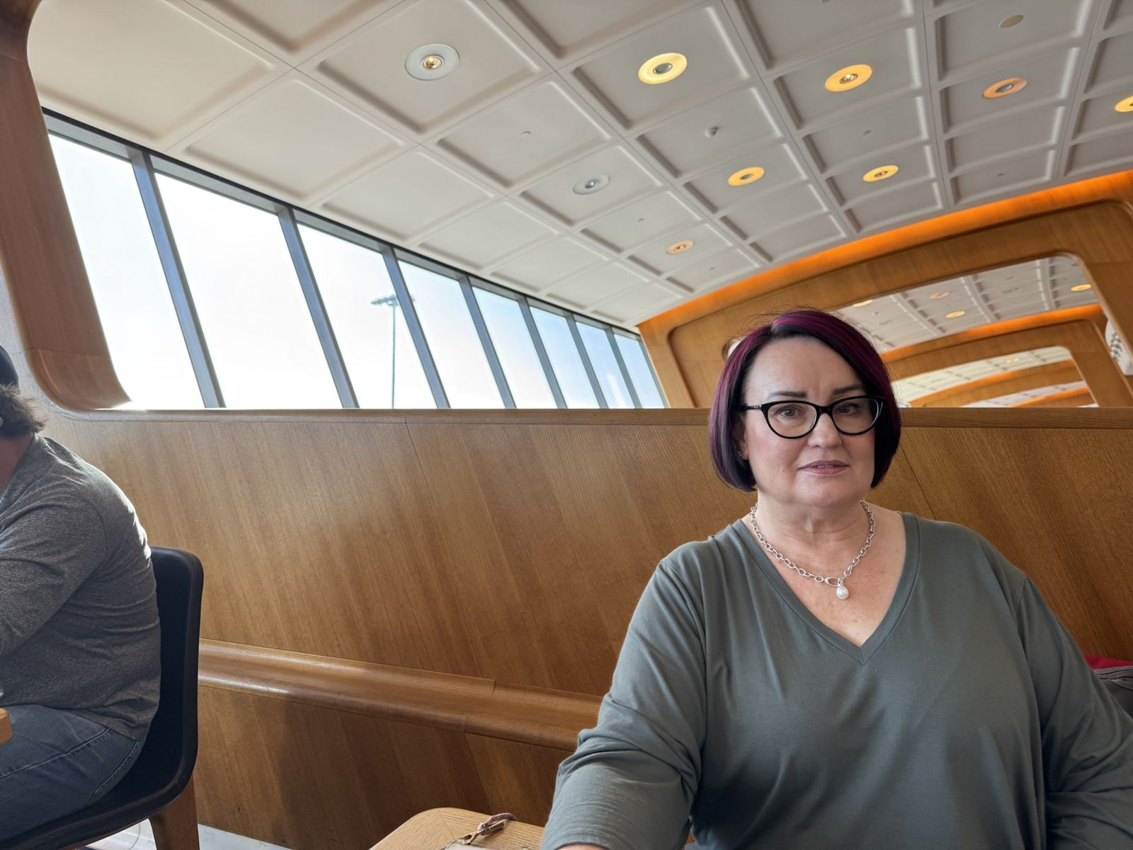 Marty sitting in the Sydney Qantas first lounge she has a grey dress on and smiling with breakfast in front of her