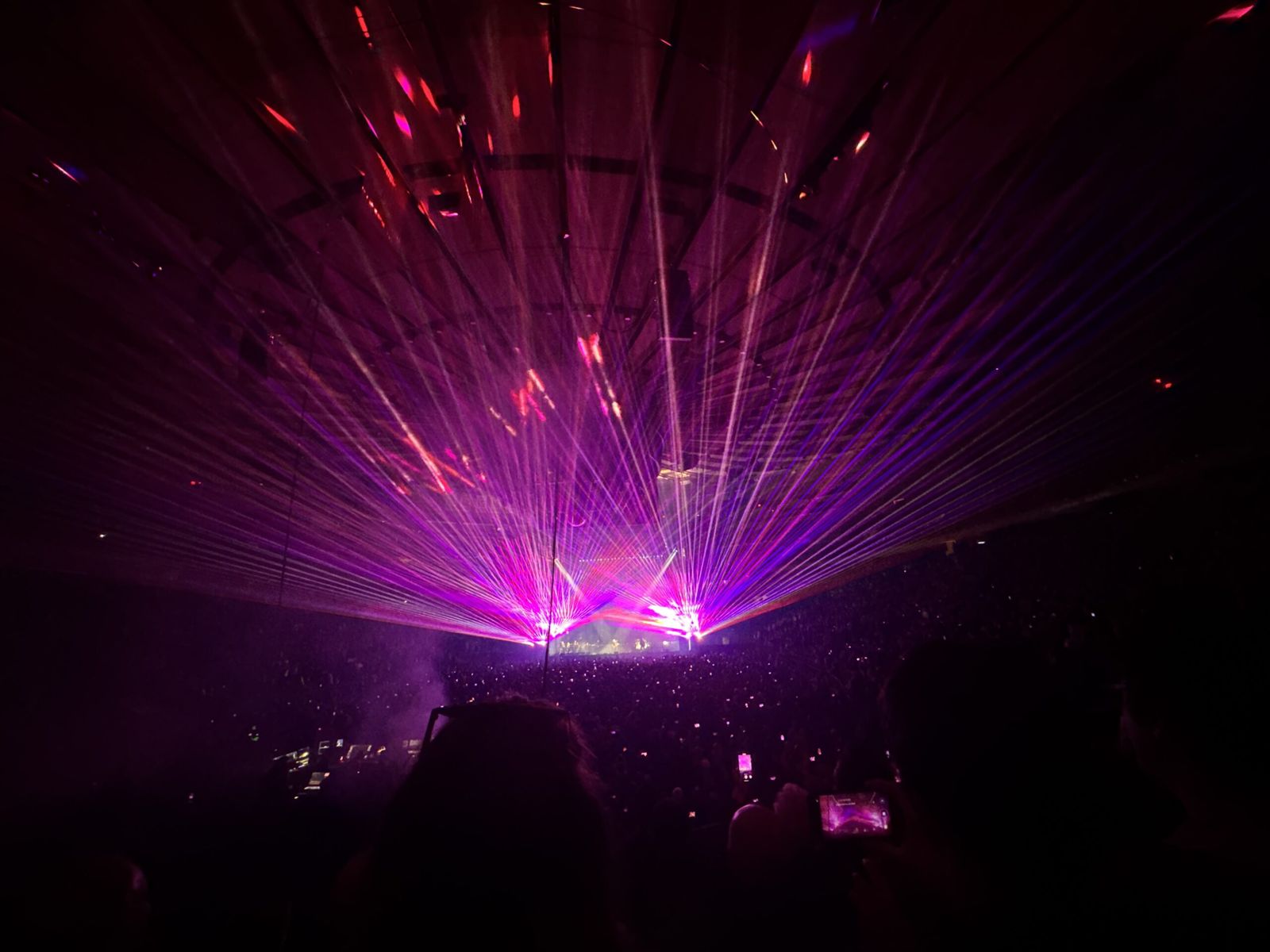 Purple lasers shine in striking lines from the stage above and around the audience