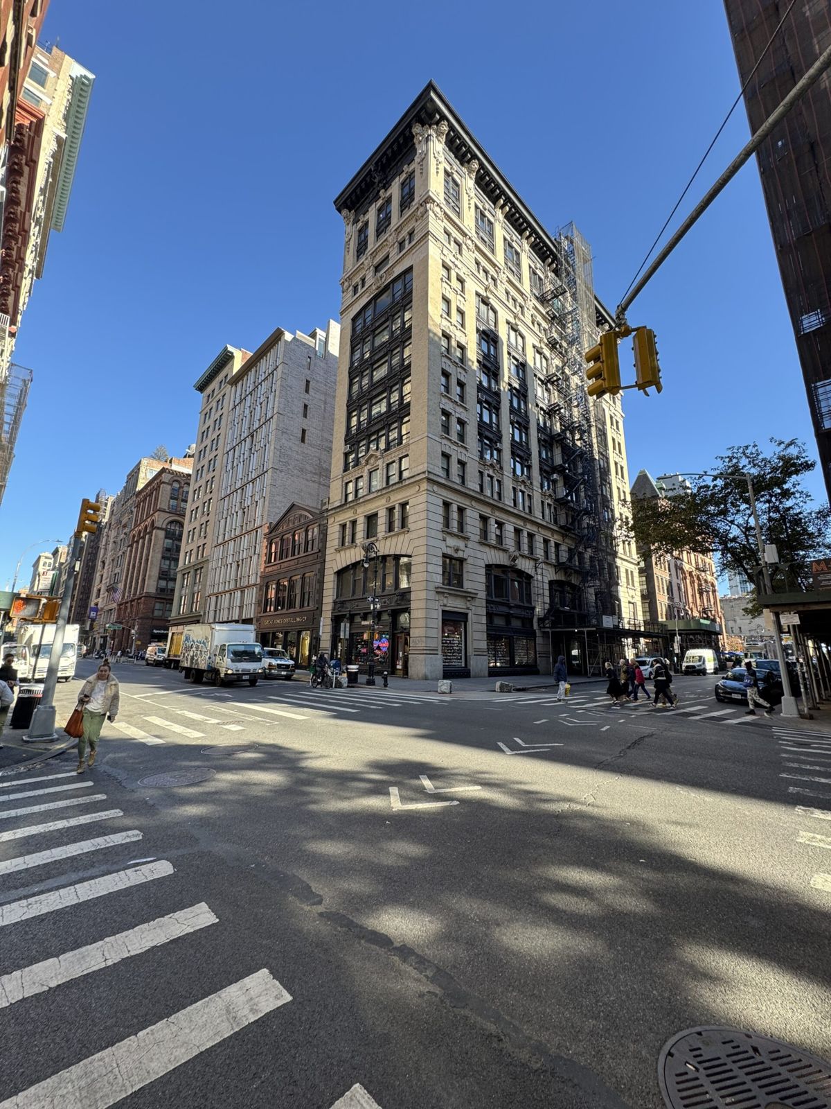 Anybody showing the architectural differences between a number of buildings along building so 10 Stories high three Stories high eight Stories high six Stories high and all of different architectural styles from brick in white to brick and red Traffic drives down the street below a sunny day