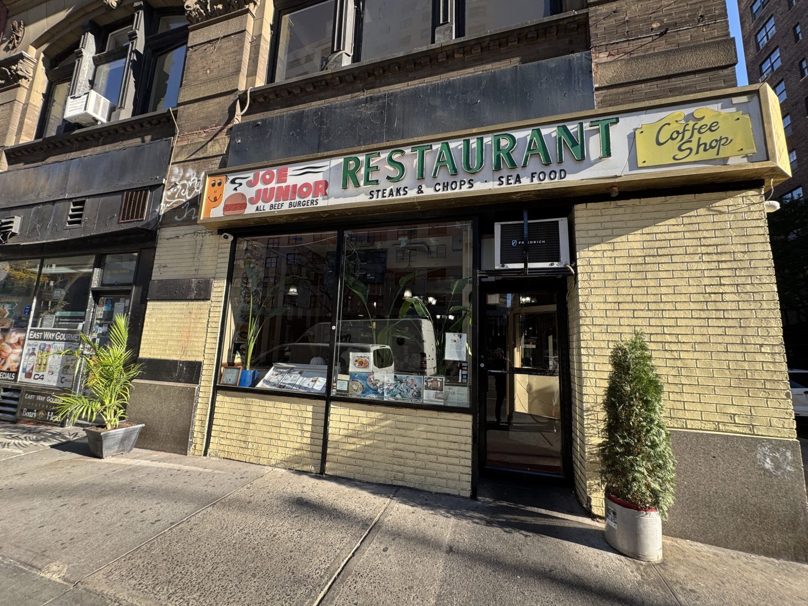 The front of Joe junior diner. Sign above, a window and yellow bricks