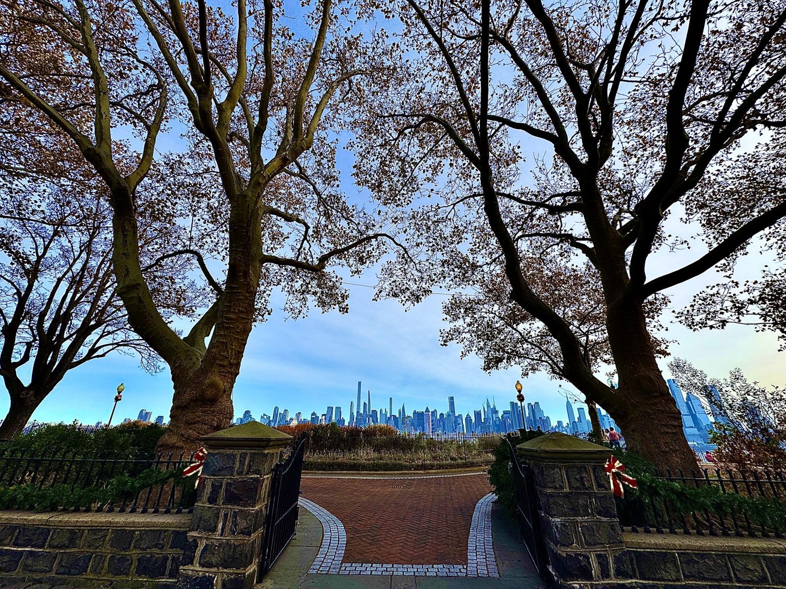 Two large trees frame a view of manhattan at the entrance to Hamilton park